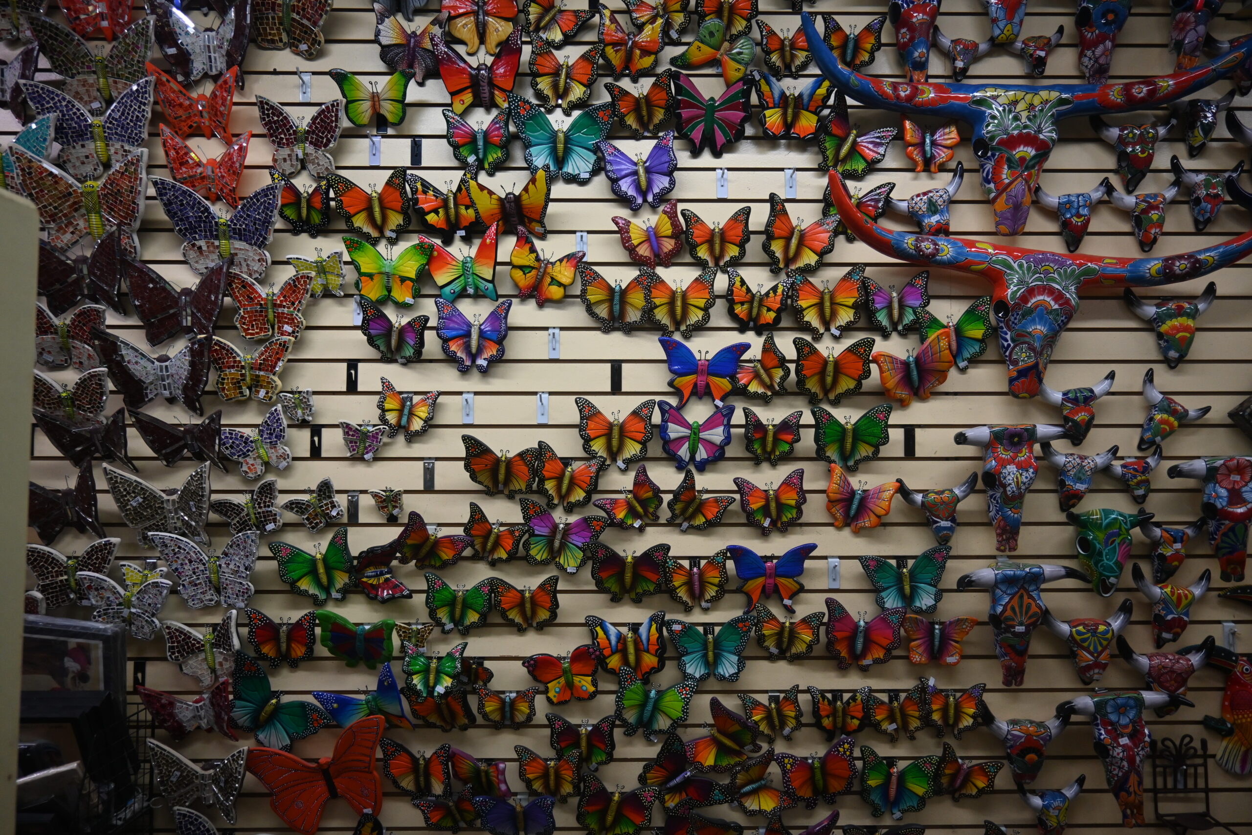 butterflies made from ceramic, glass, and other materials line the walls of a shop in San Antonio's Historic Market Square